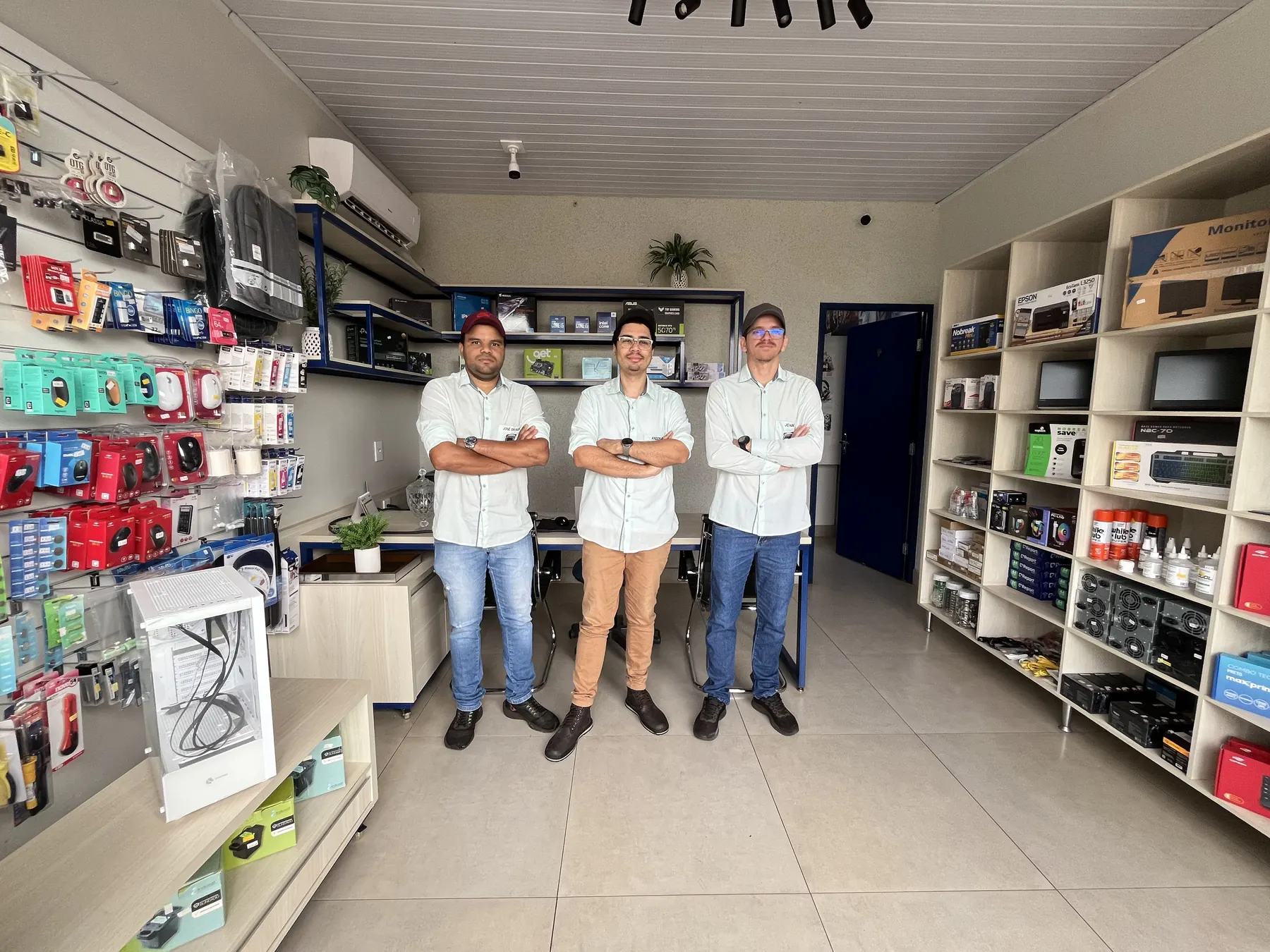 Os três técnicos da GHz dentro da loja, entre prateleiras de acessórios
